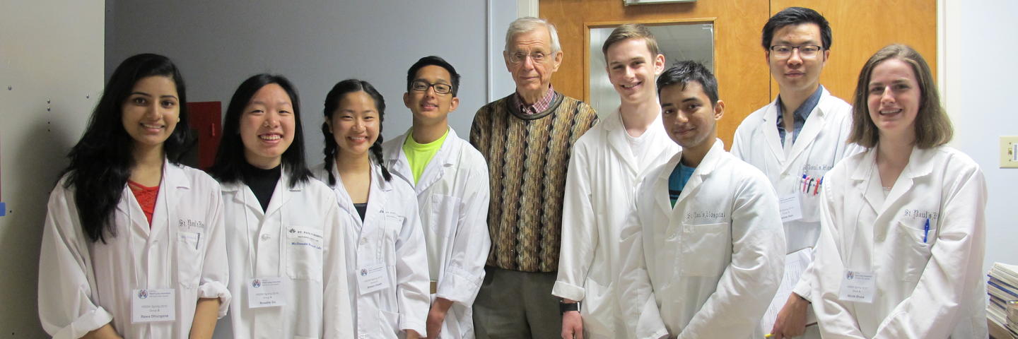 A group of people in white lab coats stand in a line