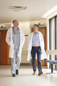 Two scientists in lab coats walk down a hallway