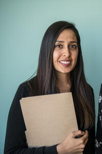 Two women stand in front of an office wall