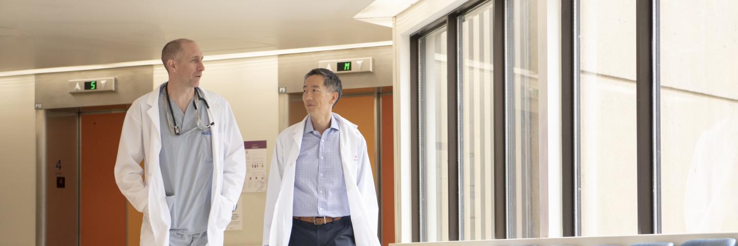 Two scientists in lab coats walk down a hallway