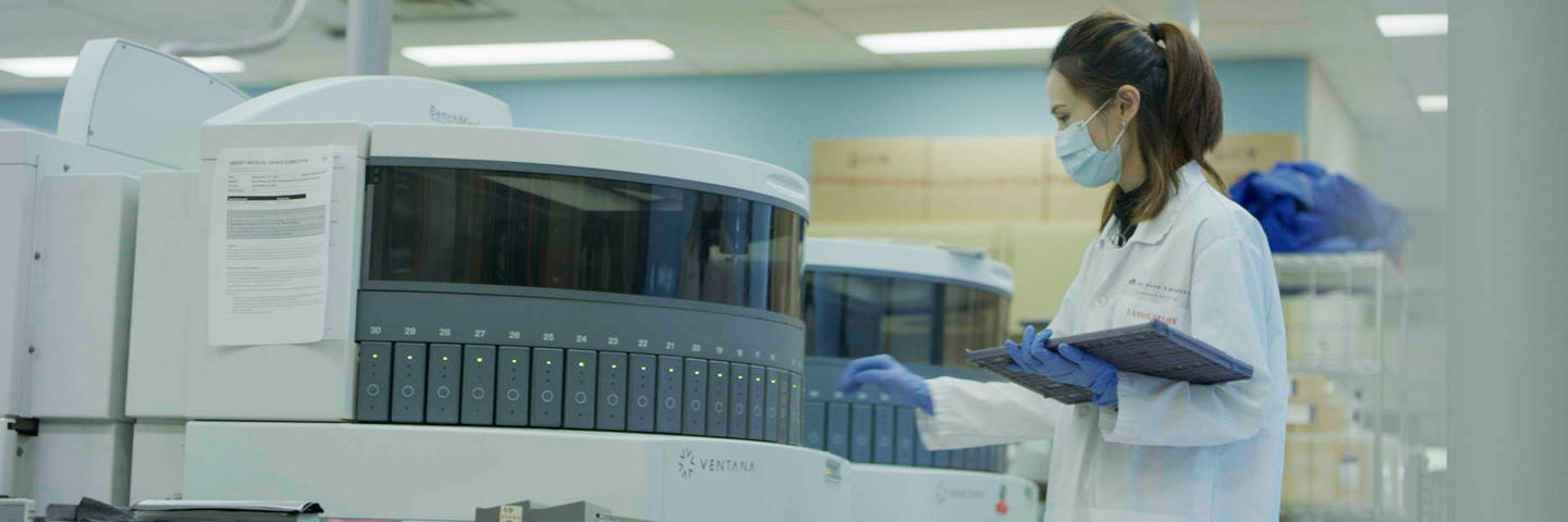 A woman in a lab stands in front of a machine