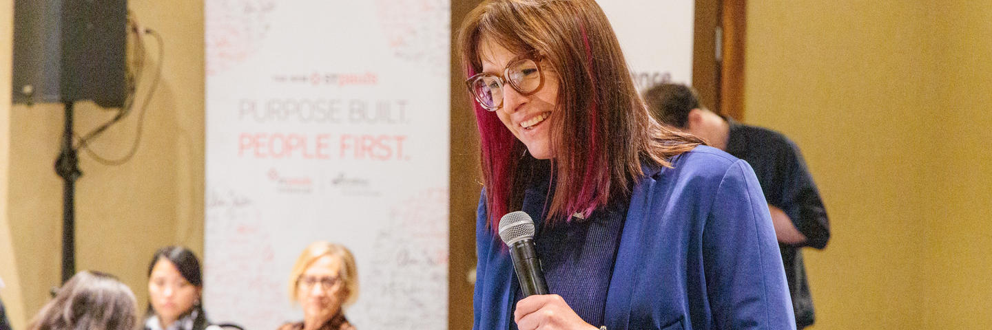 A woman with a microphone stands up speaking